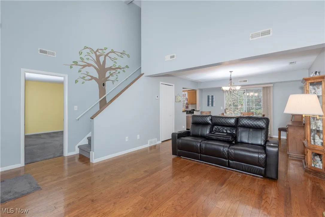 Living area with a towering ceiling, hardwood / wood-style flooring, stairway, and a chandelier