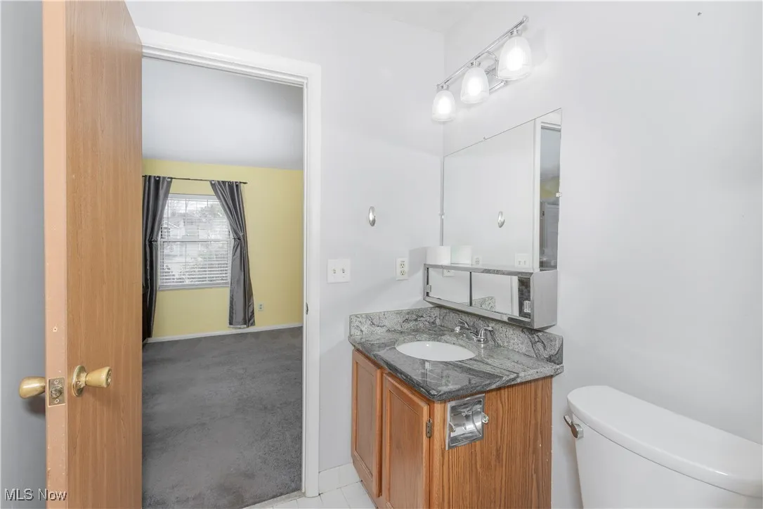 Half bath with vanity, light colored carpet, and light tile patterned flooring
