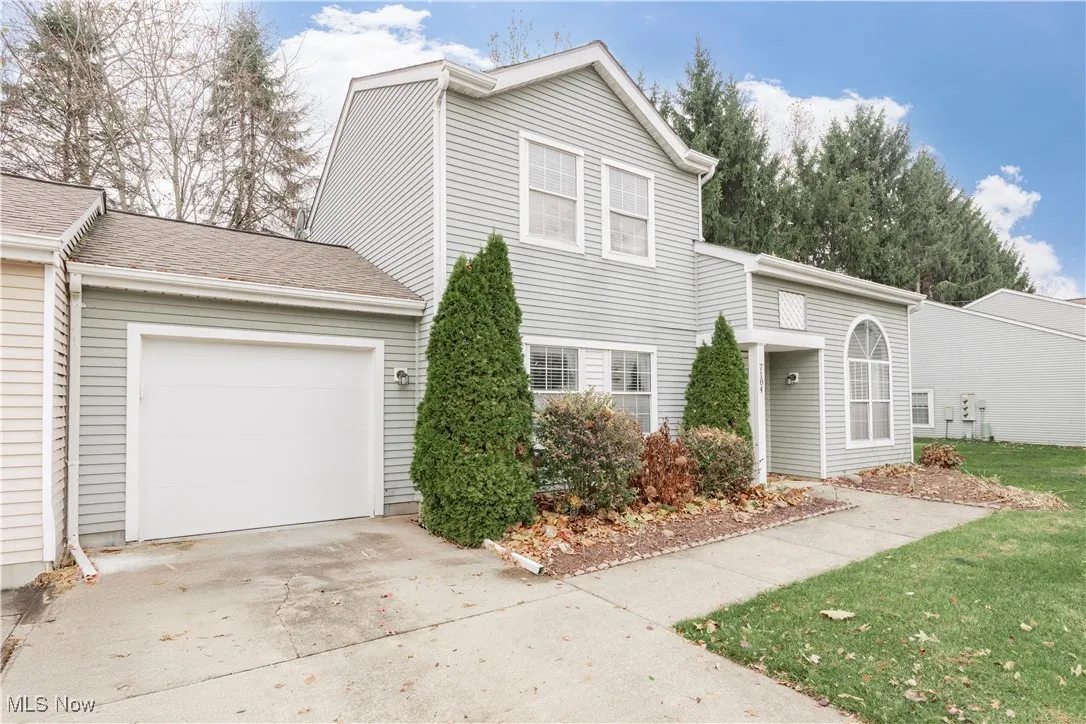 Traditional home featuring driveway, an attached garage, and roof with shingles