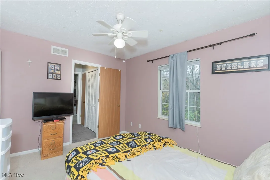 Carpeted bedroom featuring a ceiling fan, a closet, and a textured ceiling