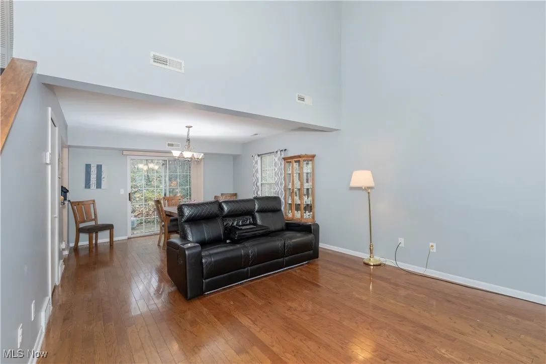 Living area featuring a chandelier, wood-type flooring, and a high ceiling