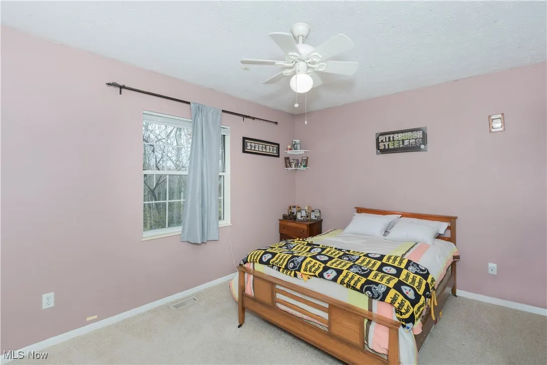 Carpeted bedroom with a ceiling fan and a textured ceiling