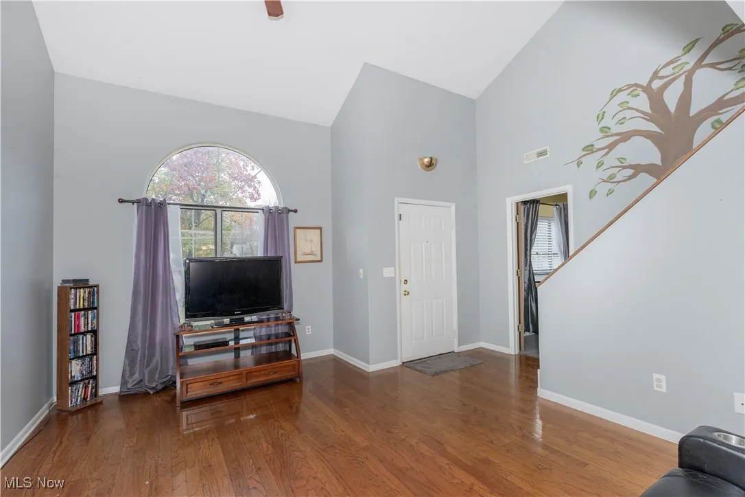 Foyer entrance with high vaulted ceiling and wood finished floors