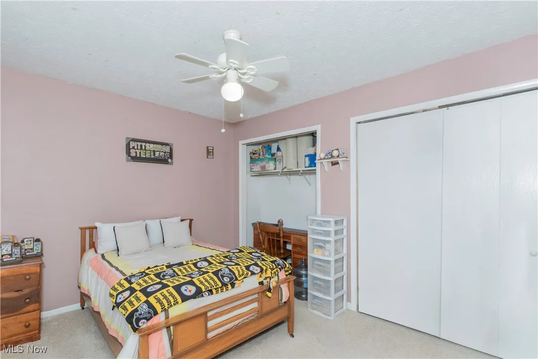 Bedroom featuring light colored carpet, a textured ceiling, a closet, and ceiling fan