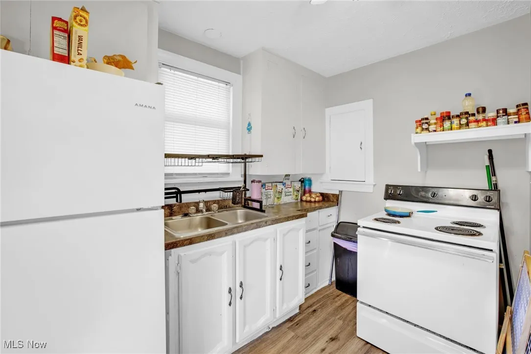 Kitchen with white cabinets, appliances, and LVT flooring