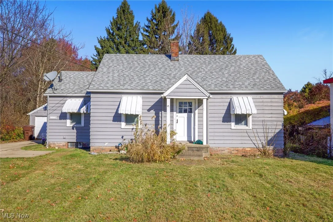 Bungalow featuring a front yard, a shingled roof, and a garage