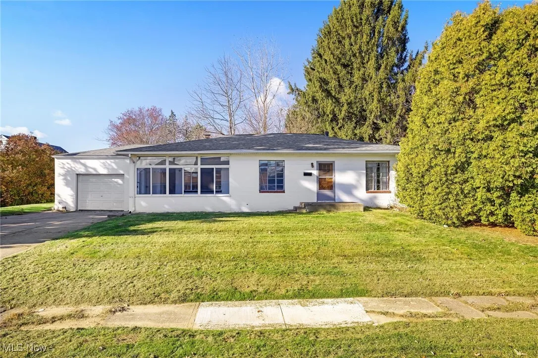 Ranch-style house with a front lawn, a garage, and driveway