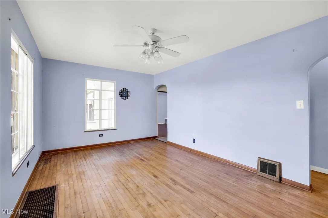 Living room with arched walkways, hardwood floors, and ceiling​​‌​​​​‌​​‌‌​‌‌​​​‌‌​‌​‌​‌​​​‌​​ fan