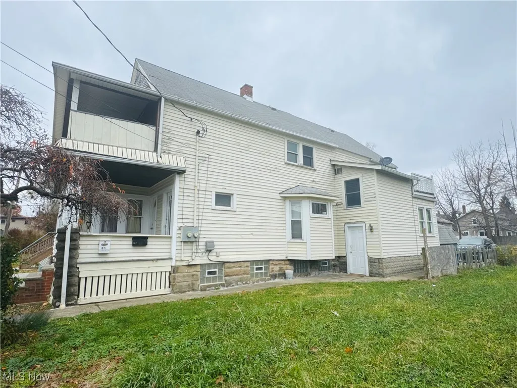 Rear view of property featuring a chimney, a balcony, a yard, and a patio area
