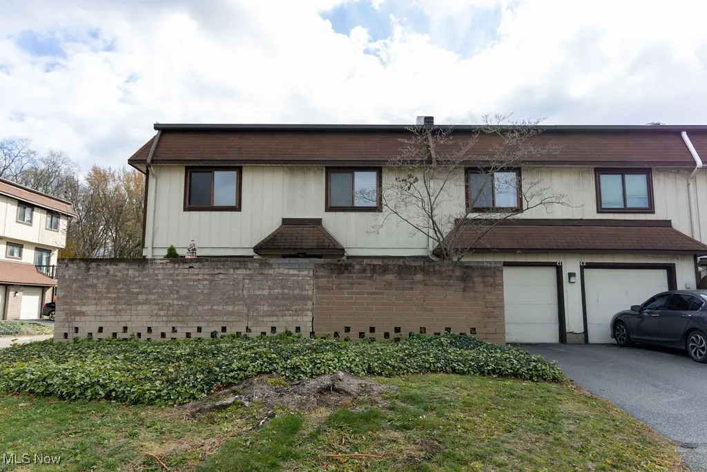 View of front of house featuring an attached garage, driveway, brick siding, and roof with shingles