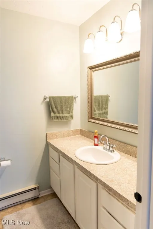 Bathroom featuring baseboard heating, vanity, and light tile patterned floors