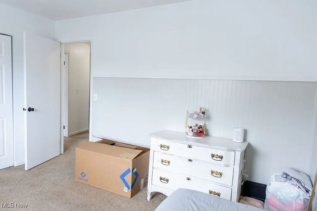 Bedroom with light carpet and wainscoting