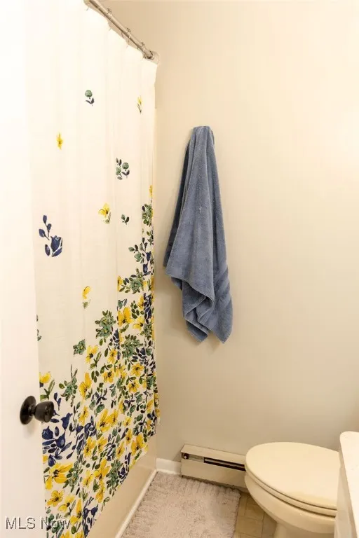 Full bath featuring a baseboard radiator and light tile patterned floors