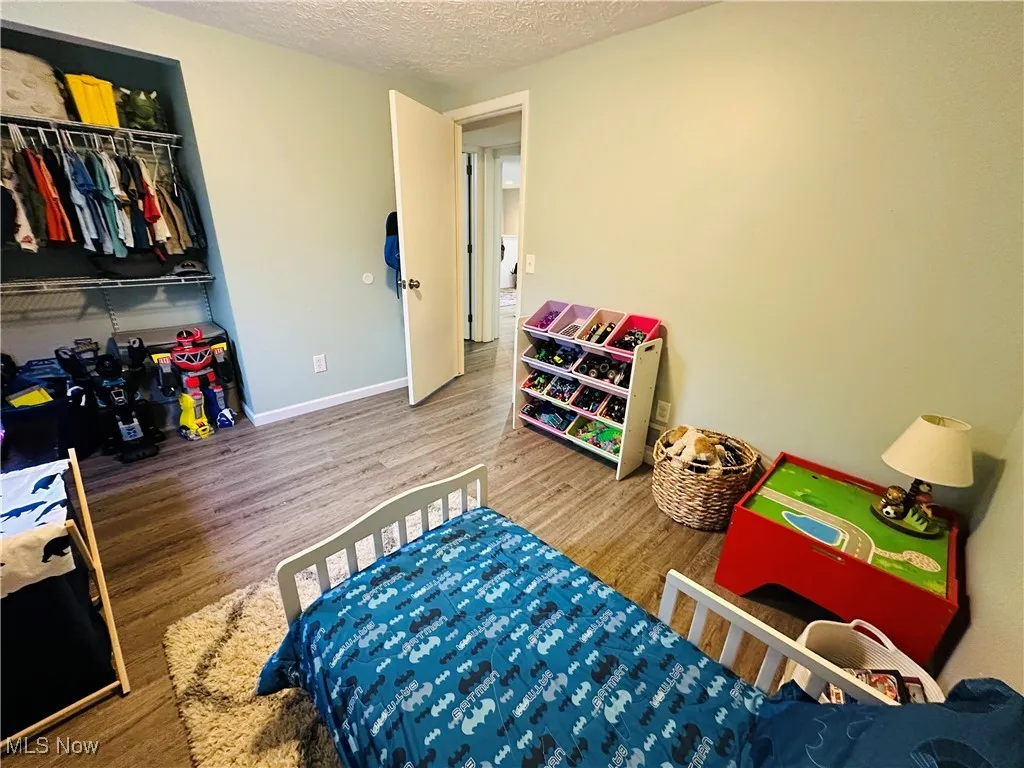 Bedroom with a textured ceiling, wood finished floors, and a closet