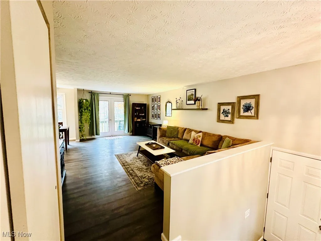 Living area featuring french doors, dark wood-type flooring, and a textured ceiling