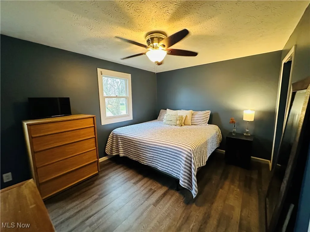 Master 1st Floor Bedroom featuring a textured ceiling, ceiling fan, and dark wood-style flooring