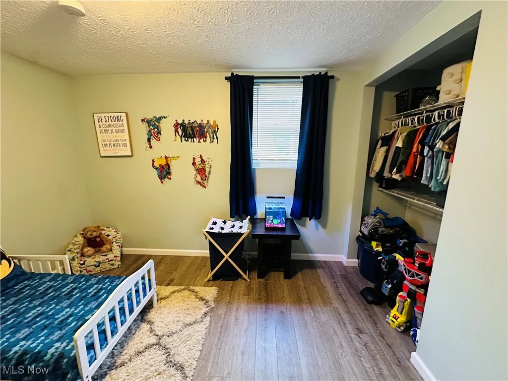Bedroom with a closet, a textured ceiling, and wood finished floors