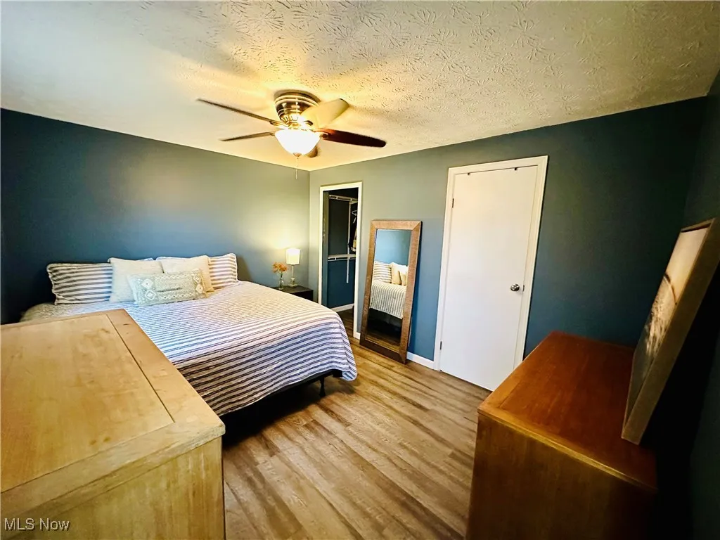Bedroom featuring a textured ceiling, a ceiling fan, wood finished floors, and a closet