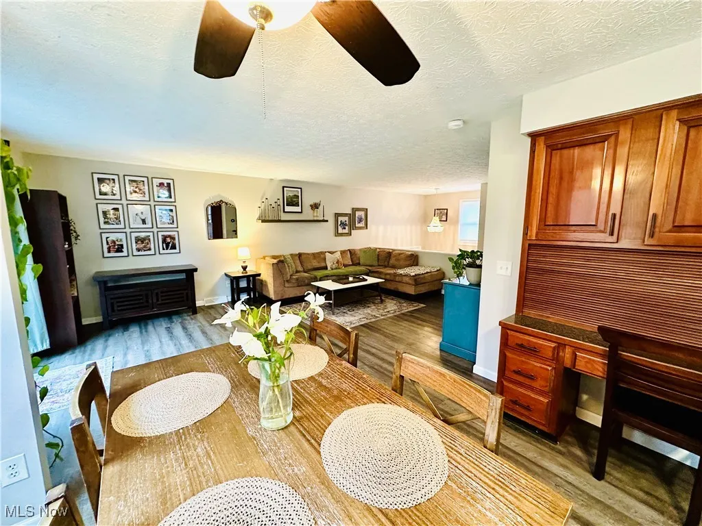 Dining room featuring a textured ceiling, light wood-style flooring, ceiling fan, and built in desk