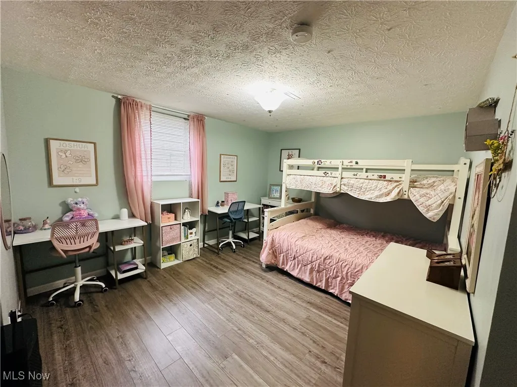 Bedroom featuring a textured ceiling, light wood-style flooring, and an office area