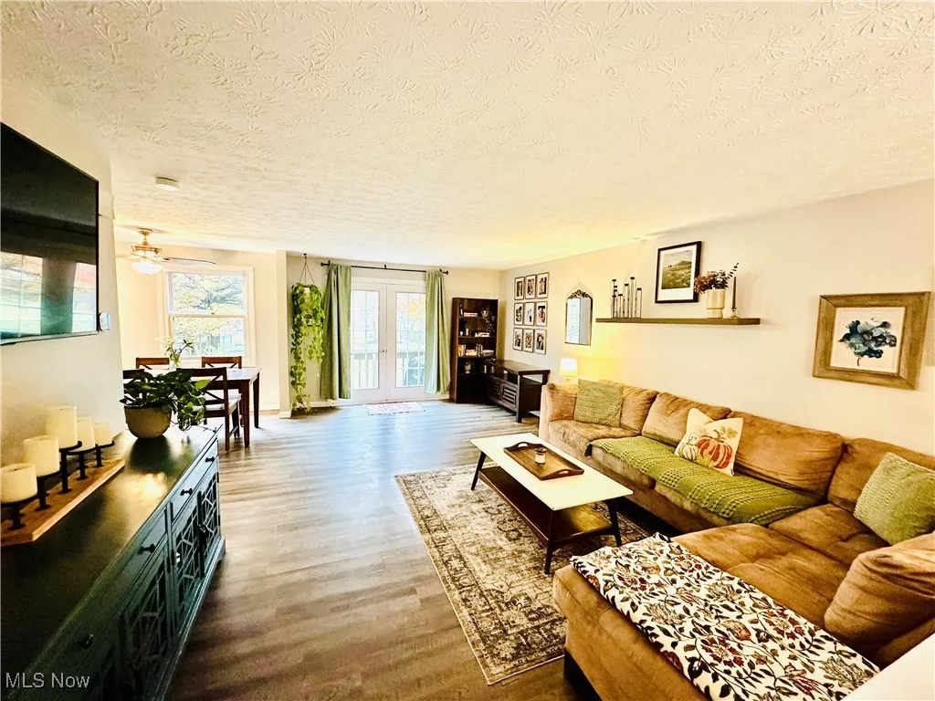 Living area with french doors, wood finished floors, a textured ceiling, and a ceiling fan