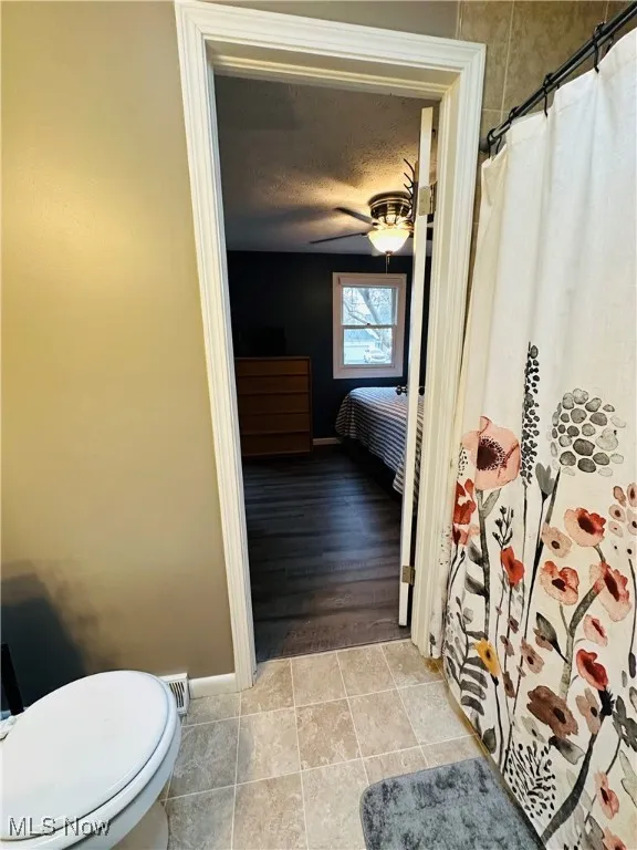Full bathroom featuring connected bathroom, a shower with curtain, a textured ceiling, and light tile patterned flooring