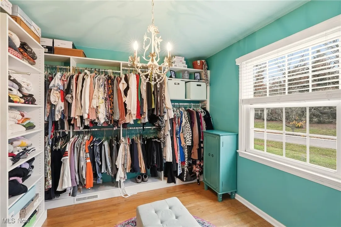 Spacious closet with a chandelier and light wood finished floors