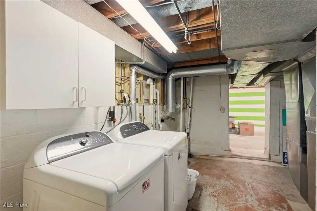 Laundry room with washing machine and clothes dryer, heating unit, and concrete floors