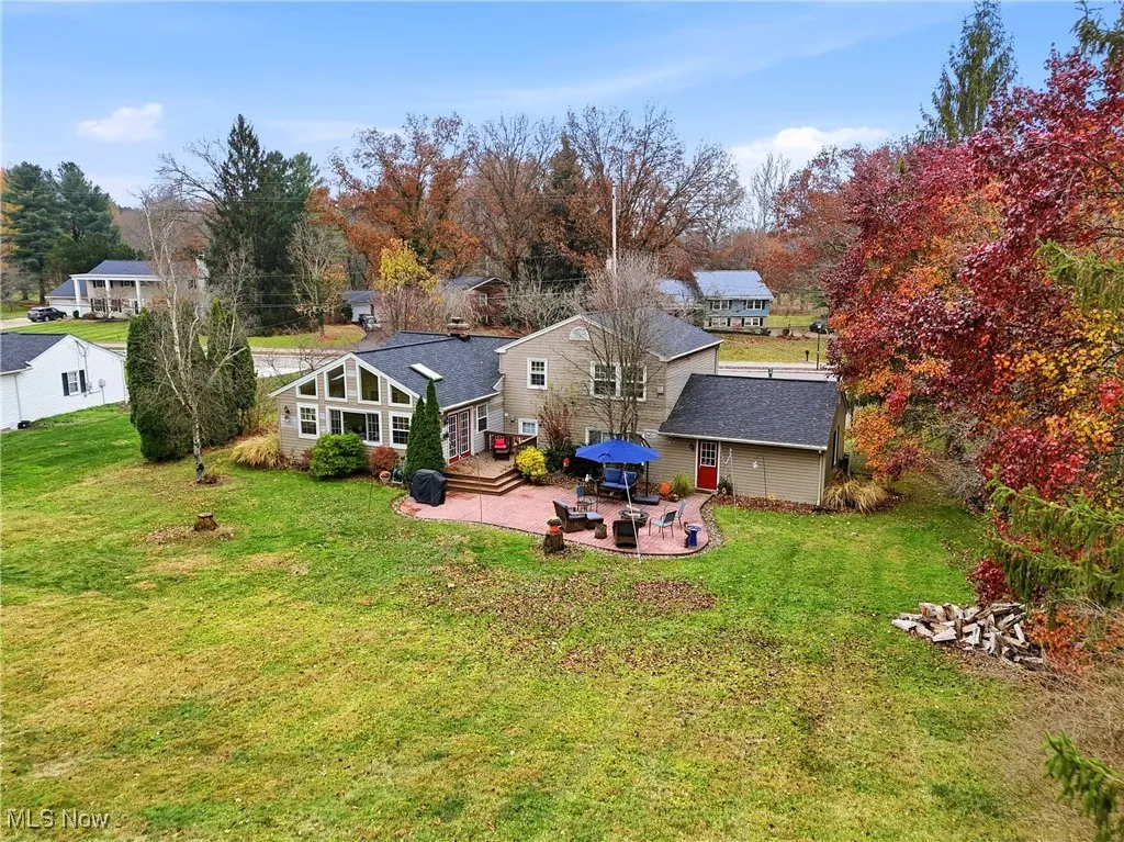 Rear view of property with a patio area, a lawn, and a shingled roof