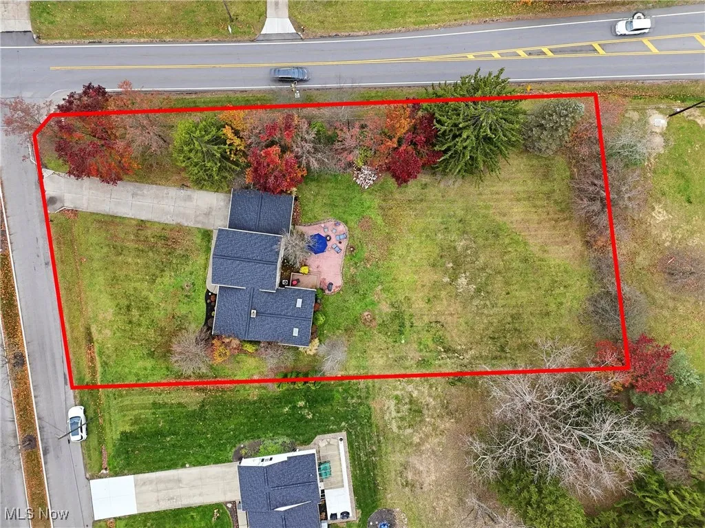 Split-level home featuring driveway, a chimney, a front yard, brick siding, and a shingled roof