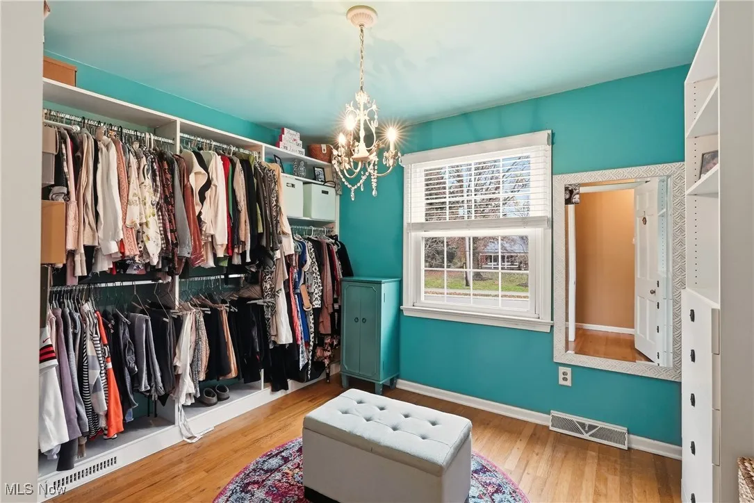Walk in closet with a chandelier and wood-type flooring