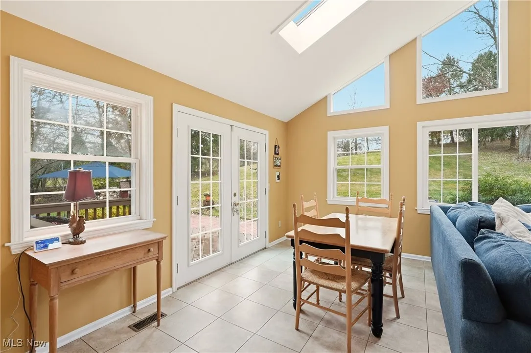 Sunroom / solarium featuring a skylight, french doors, and vaulted ceiling