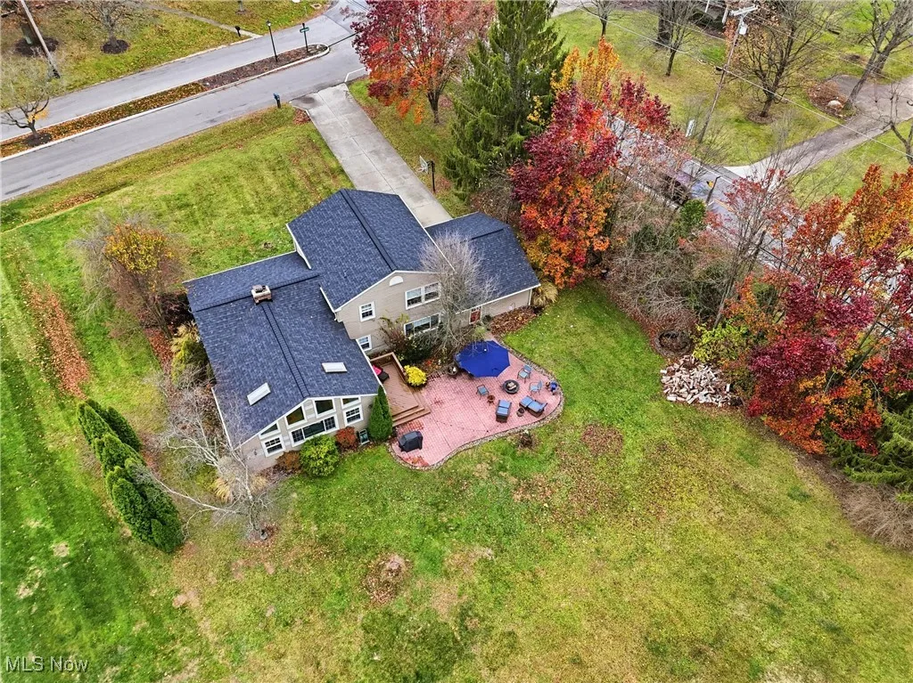 Split-level home featuring driveway, a chimney, a front yard, brick siding, and a shingled roof