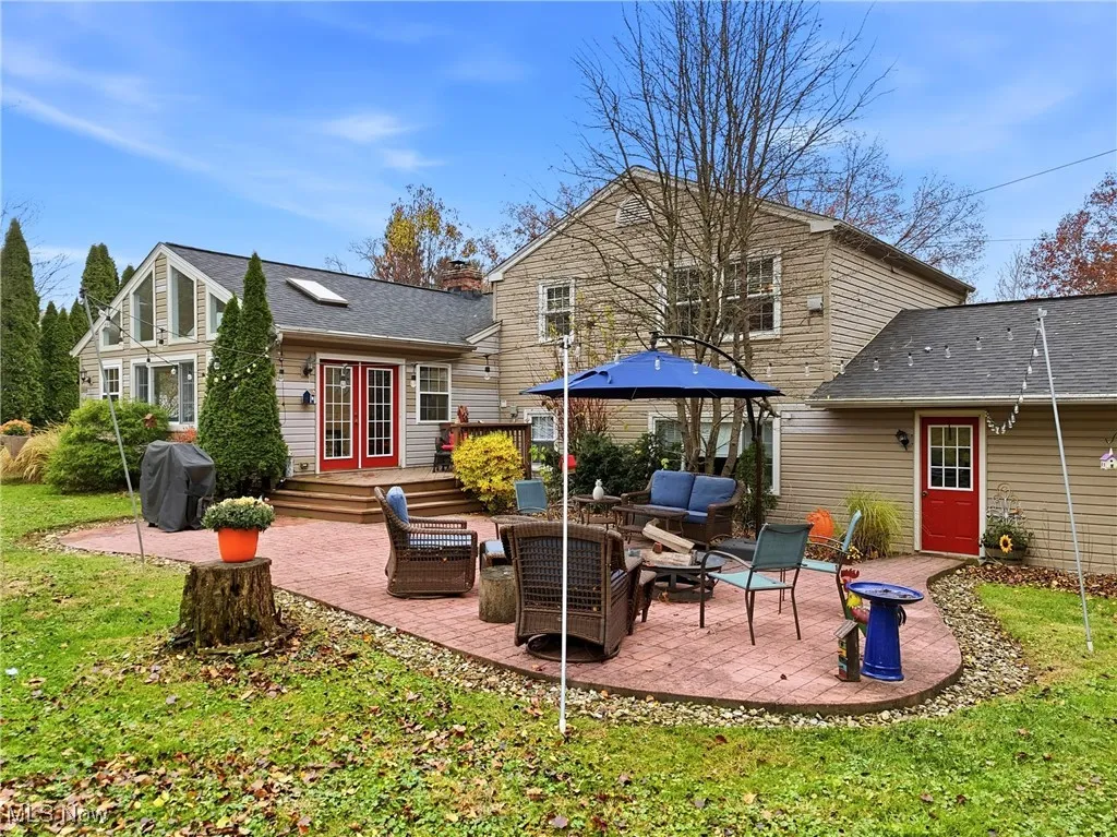 Back of property featuring a patio, outdoor lounge area, a shingled roof, and a lawn