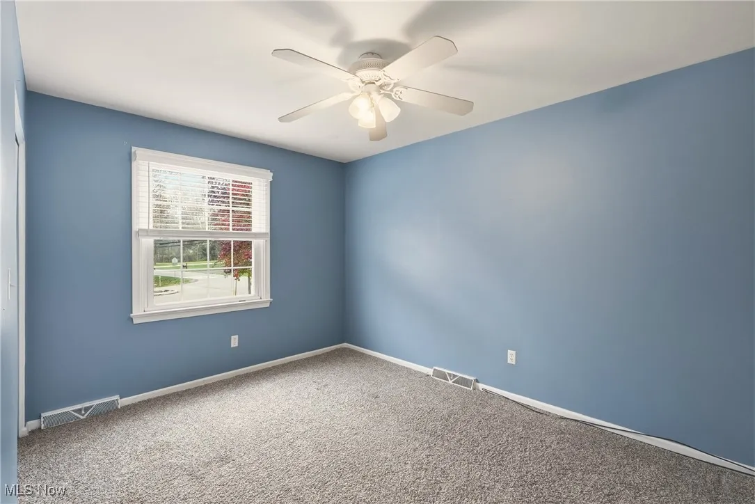 Unfurnished room featuring carpet and a ceiling fan