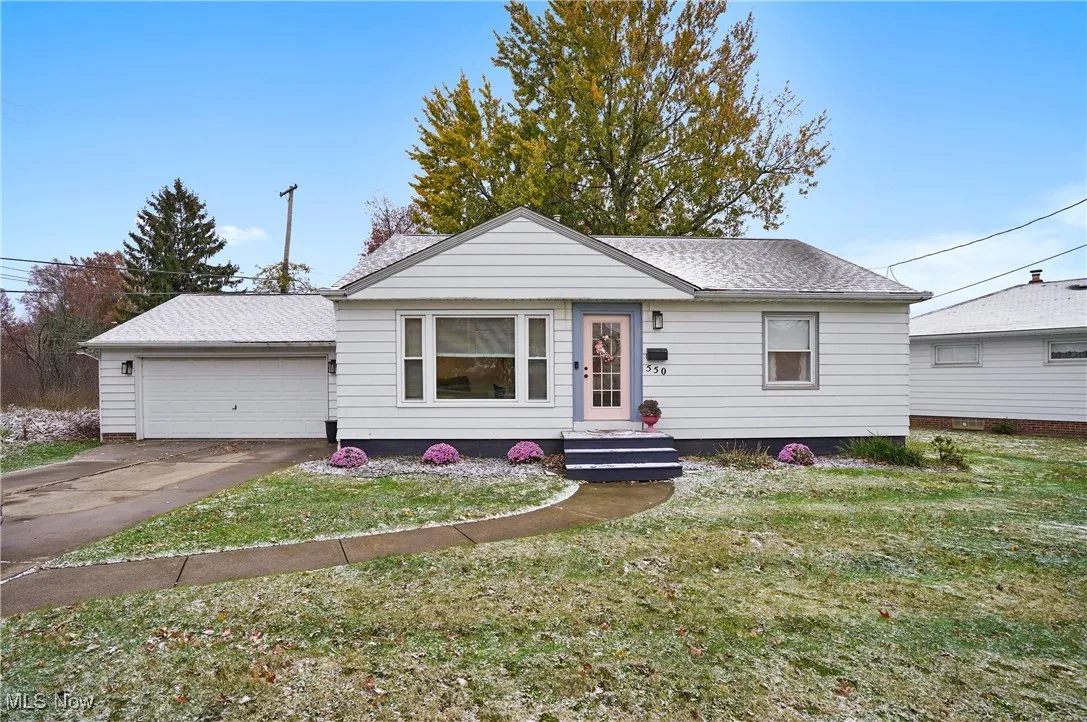 View of front of house featuring a front lawn, a garage, and roof with shingles