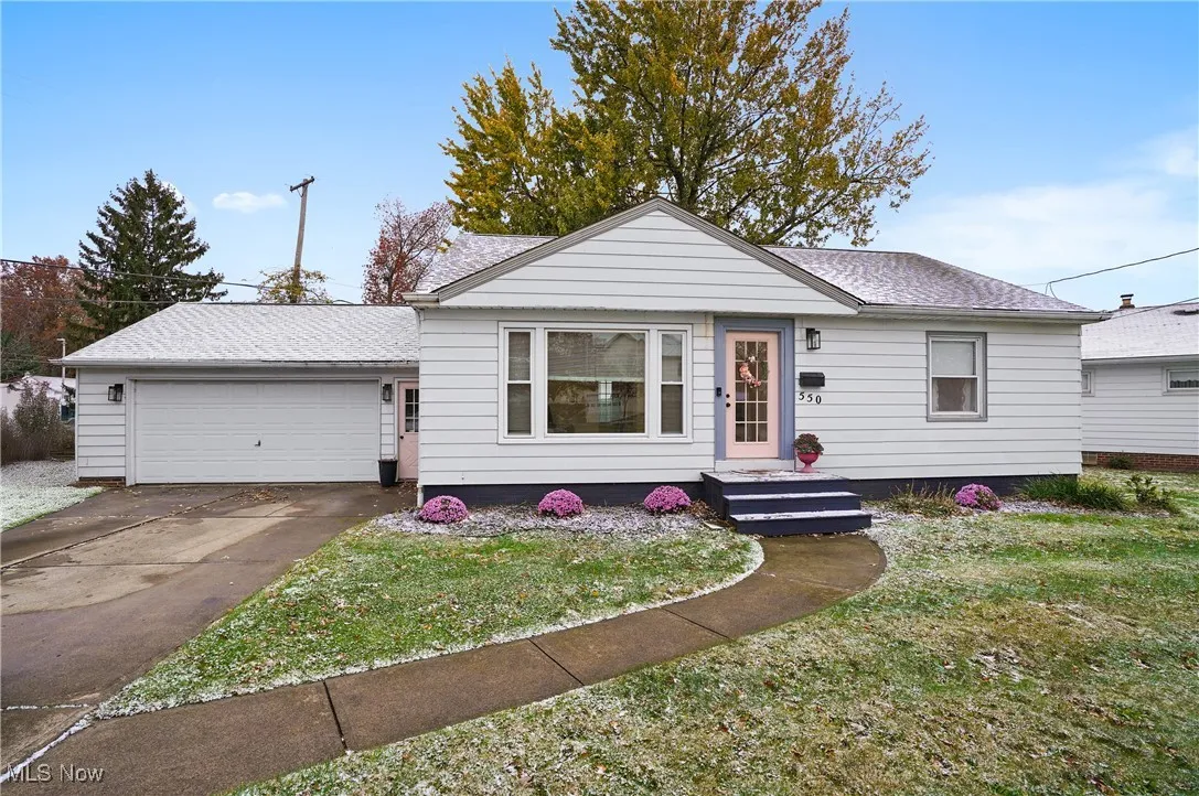 View of front of home with a front yard, a garage, roof with shingles, and concrete driveway