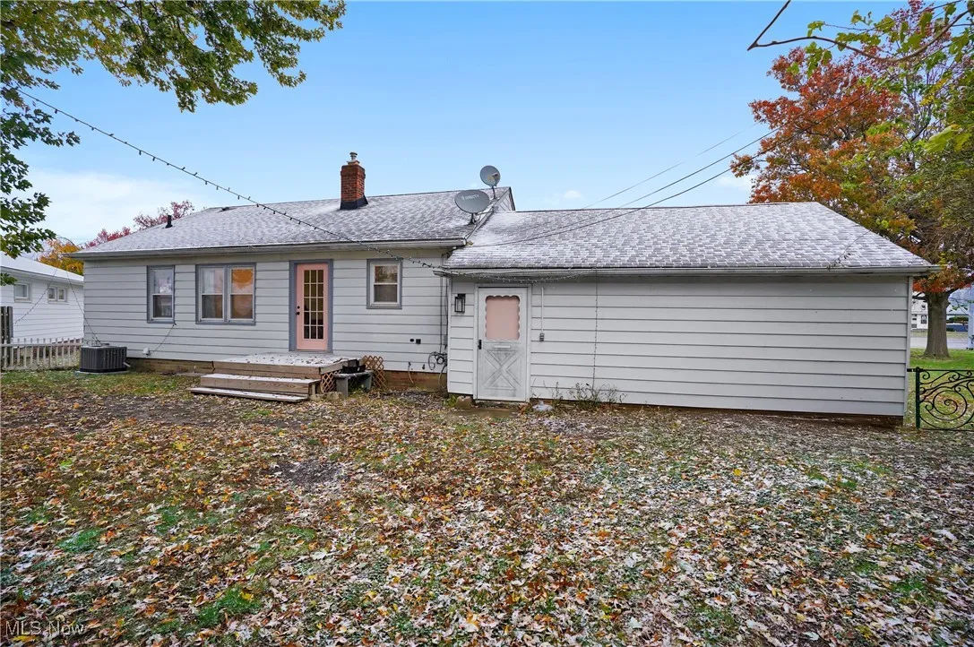 Rear view of house featuring a chimney and a shingled roof