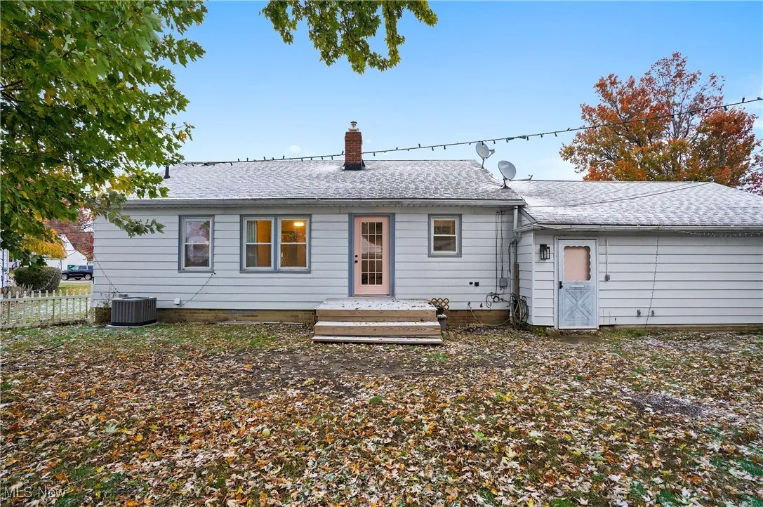 Rear view of house featuring roof with shingles and a chimney