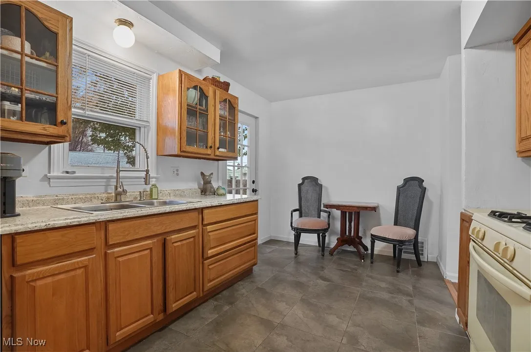 Kitchen with glass insert cabinets, white range with gas stovetop, and brown cabinetry