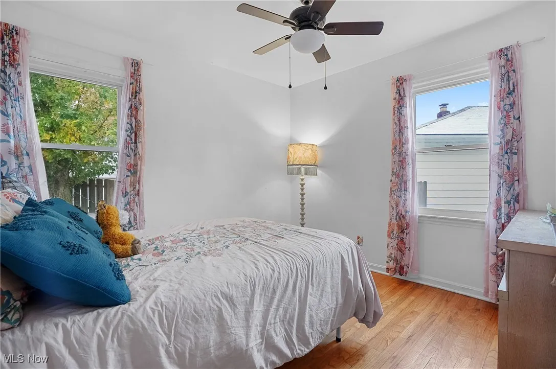 Bedroom featuring hardwood / wood-style floors, a ceiling fan, and multiple windows