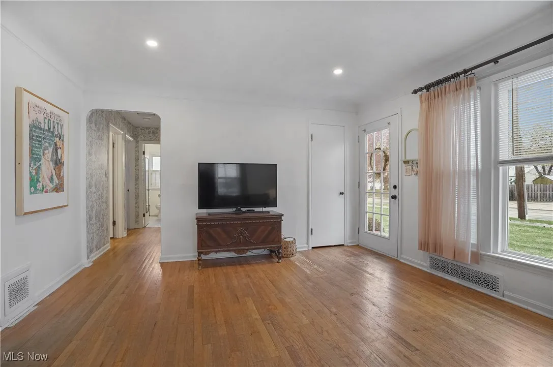Unfurnished living room featuring light wood-style flooring, arched walkways, and recessed lighting