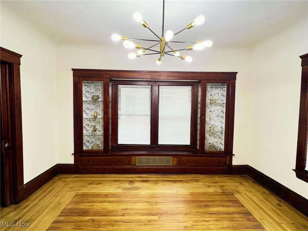 Unfurnished dining area featuring hardwood / wood-style flooring and a chandelier