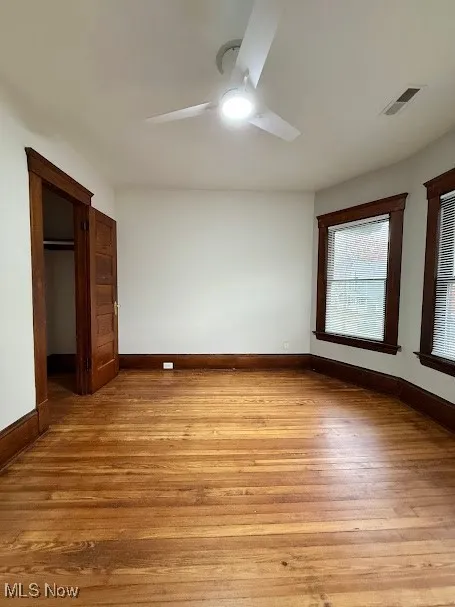 Unfurnished bedroom with hardwood / wood-style flooring, ceiling fan, and a spacious closet