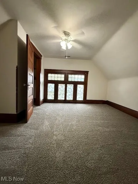 Bonus room featuring carpet flooring, a ceiling fan, vaulted ceiling, and a textured ceiling