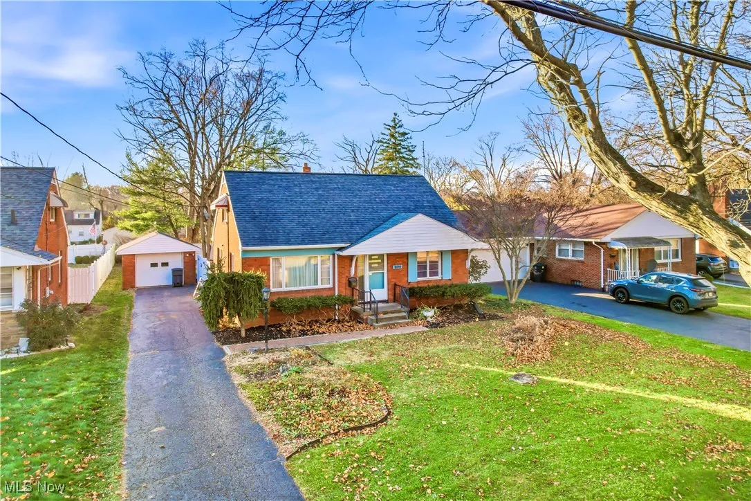 View of front of home with an outbuilding, a front yard, brick siding, and asphalt driveway
