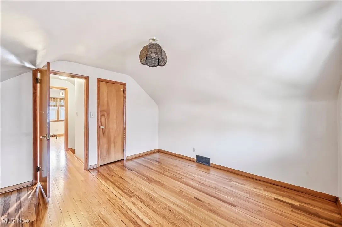 Bonus room with vaulted ceiling and light wood-style floors
