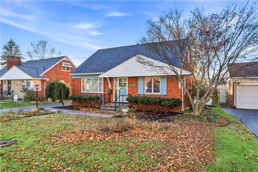 Bungalow featuring a front lawn, a shingled roof, brick siding, and a garage