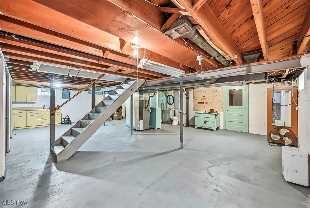 Below grade area with stairway, heating unit, and electric panel