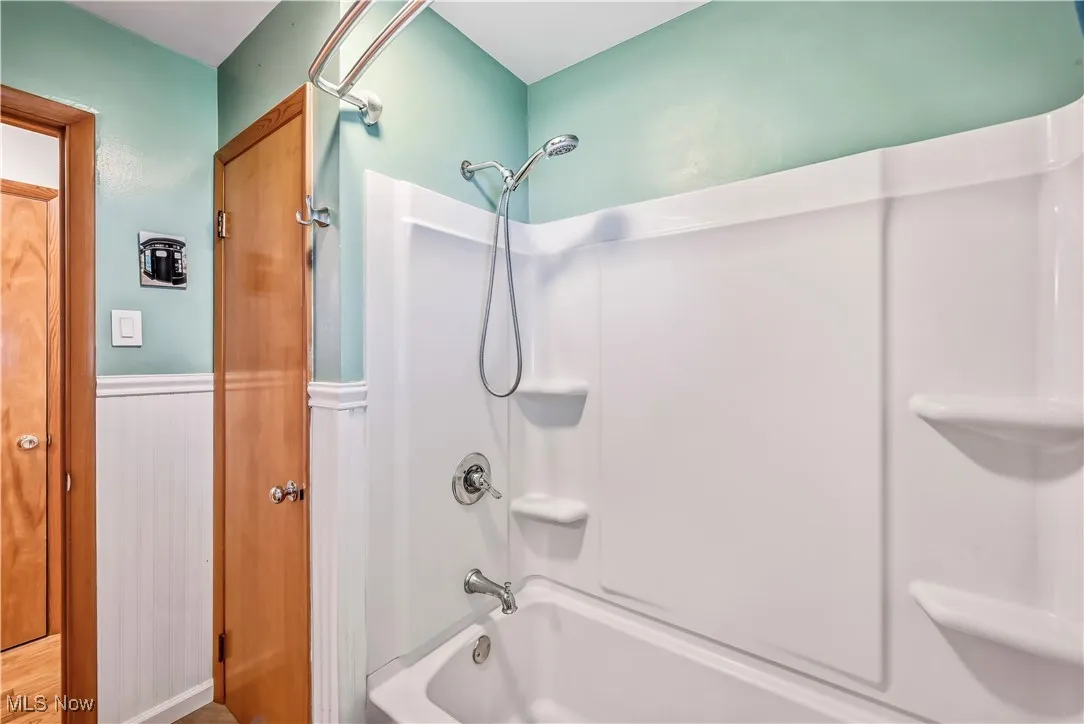 Bathroom featuring bathtub / shower combination and wainscoting